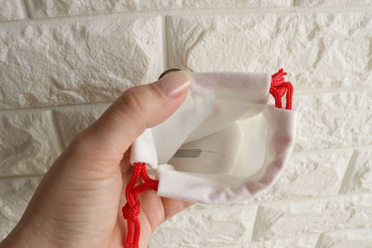 女性の手が白い巾着袋の中にAirPodsケースを入れている