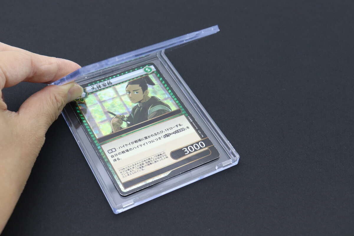 透明なクリアケースにトレーディングカードを入れようとしている手元