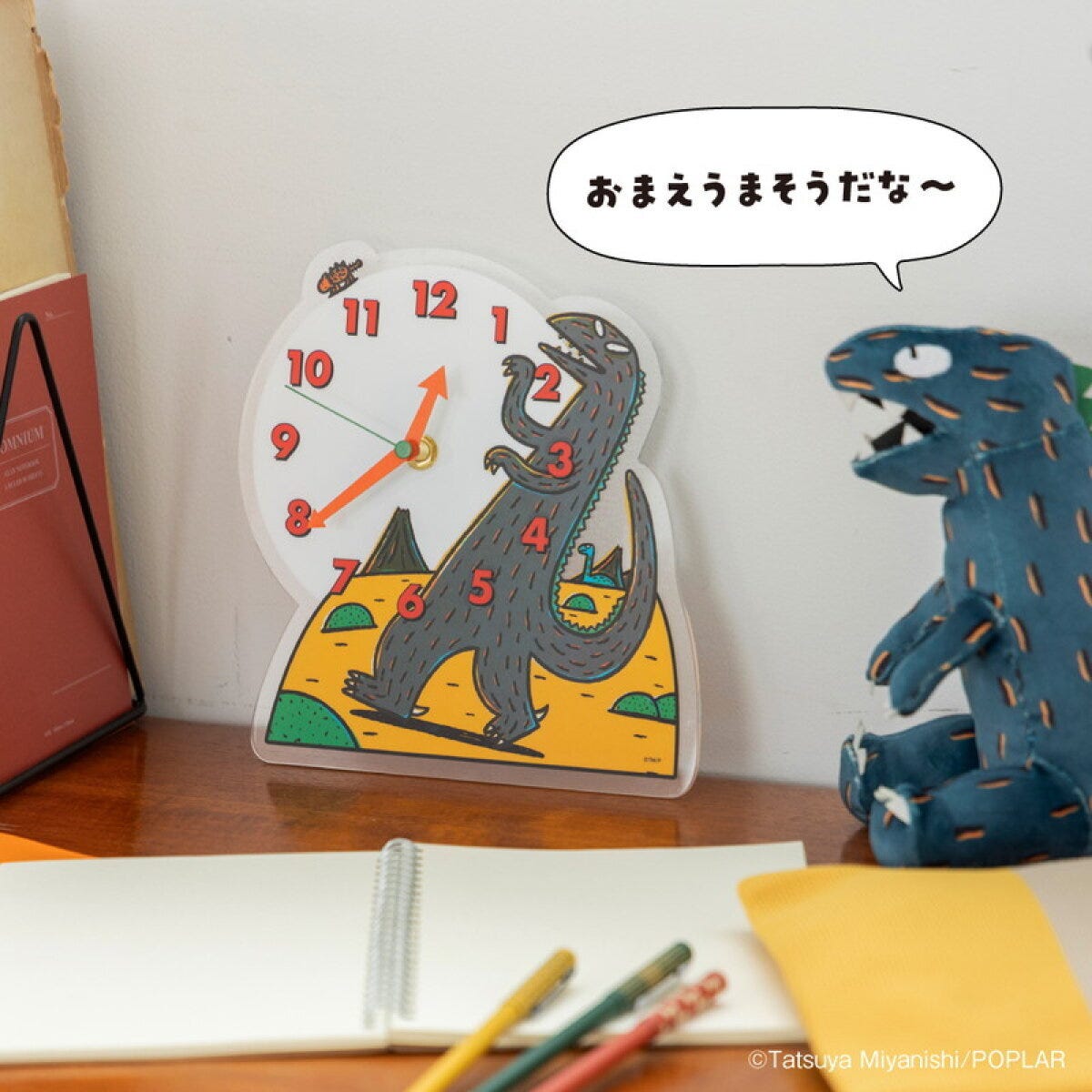 絵本「おまえうまそうだな」のティラノサウルスが描かれたアクリル時計と、ティラノサウルスのぬいぐるみ