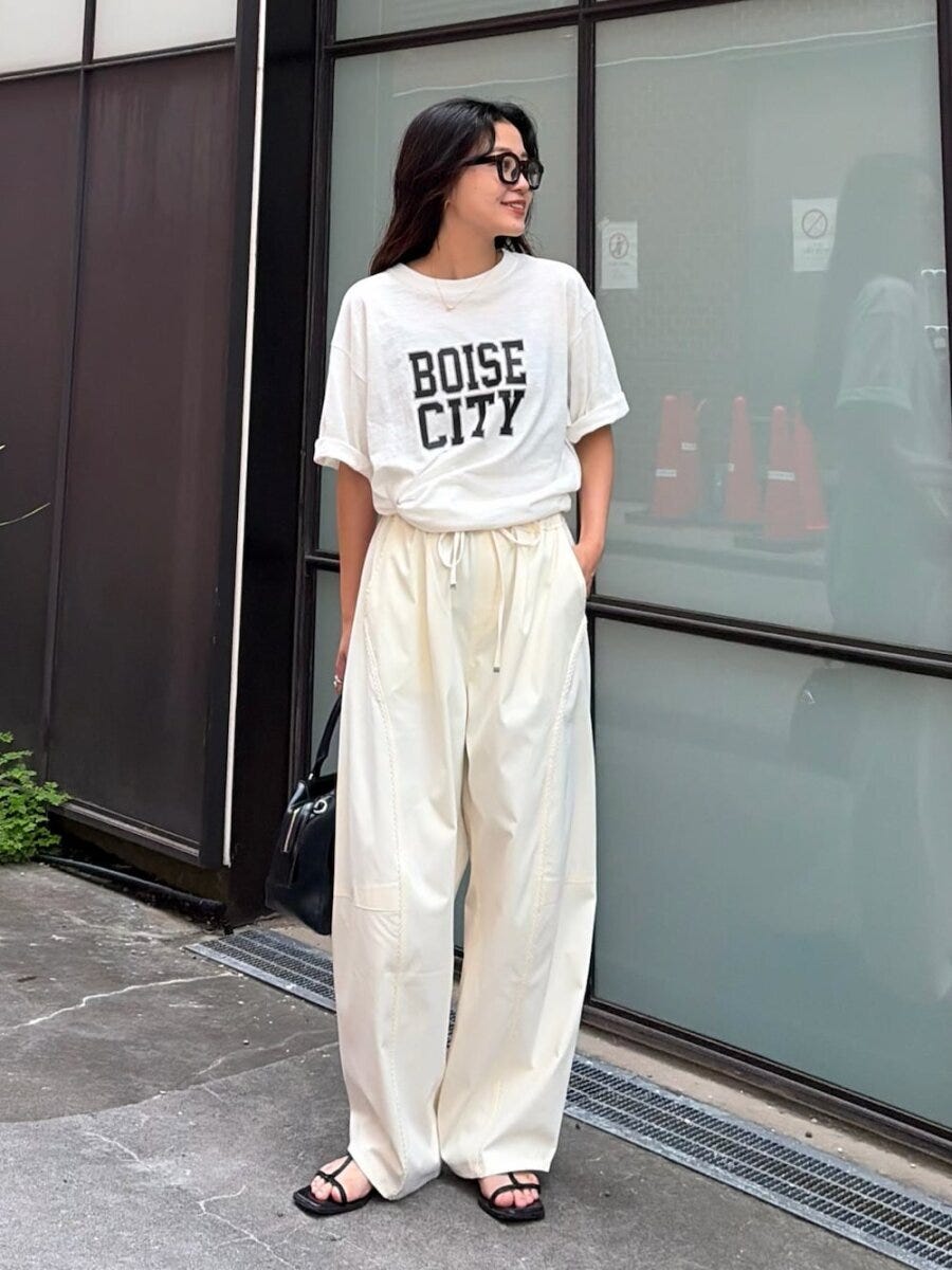 黒縁メガネの女性が白Tシャツと白バレルパンツで立つ全身 黒縁メガネの女性が白Tシャツと白バレルパンツで立つ全身