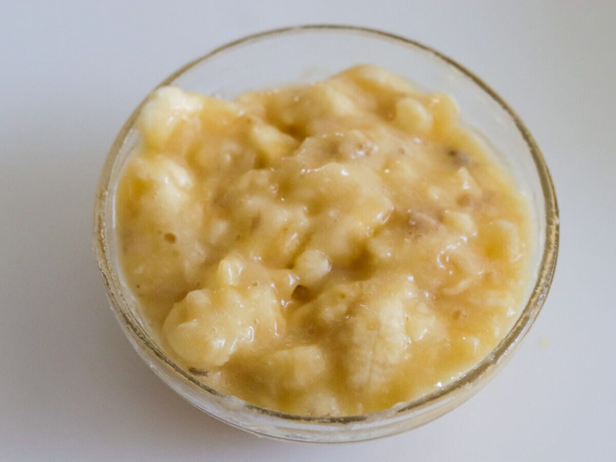 ガラスボウルでフォークを使い粗くつぶしたバナナ