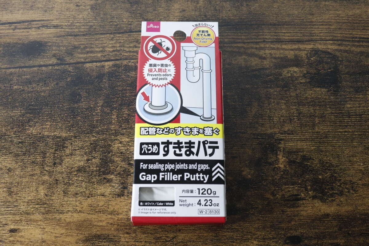 木目のテーブルに置かれたダイソーすきまパテのパッケージ 木目のテーブルに置かれたダイソーすきまパテのパッケージ