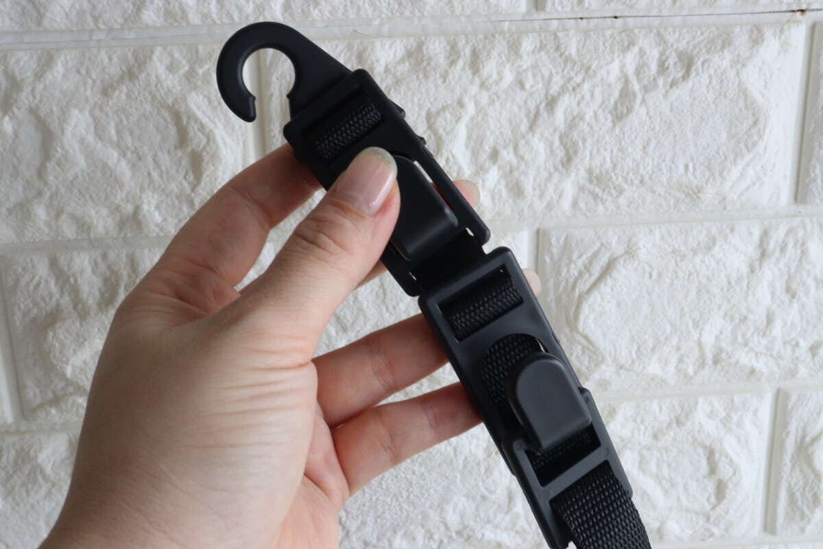 女性の手がヘッドレスト用お買い物フックのベルト部分を持つ 女性の手がヘッドレスト用お買い物フックのベルト部分を持つ