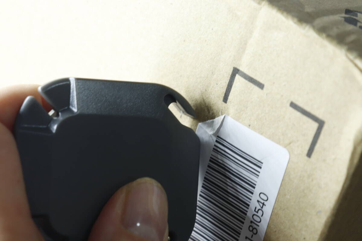 3WAY開封カッターで段ボールのラベルを剥がし始める手元 3WAY開封カッターで段ボールのラベルを剥がし始める手元