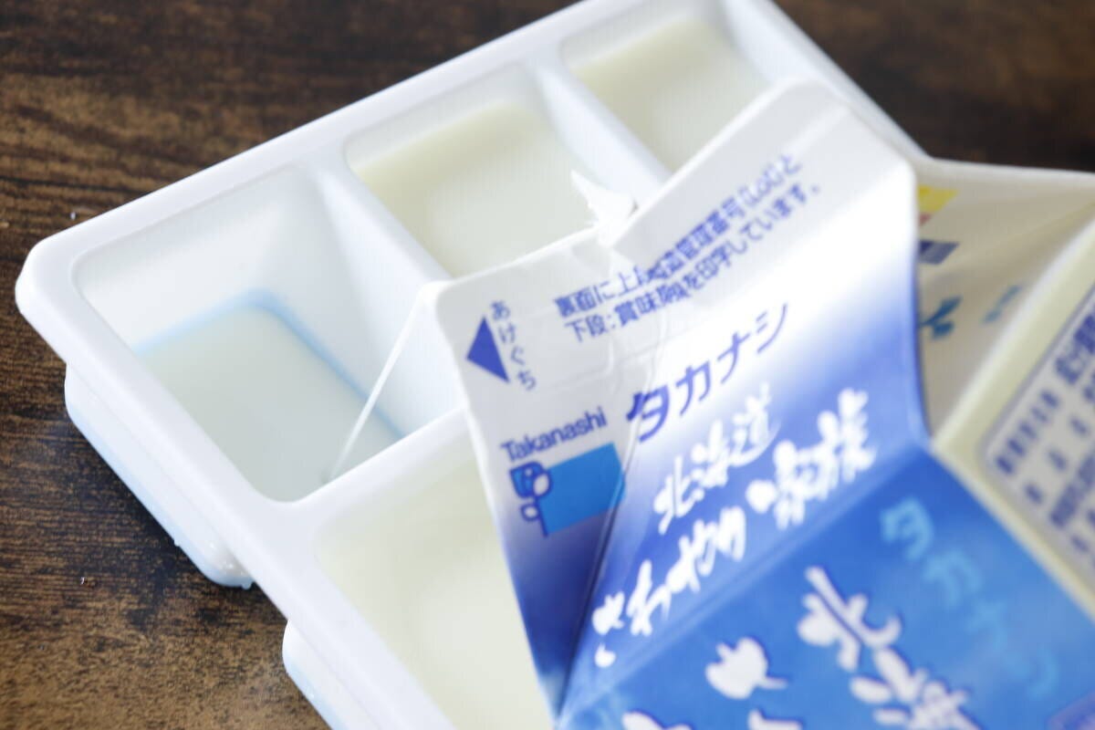 白い製氷皿のくぼみに牛乳パックから牛乳を注いでいる様子