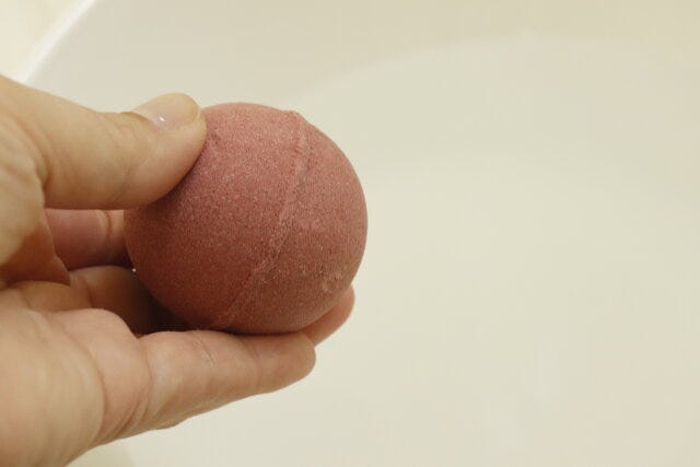 ダイソーのピザバスボールを湯桶に投入する様子