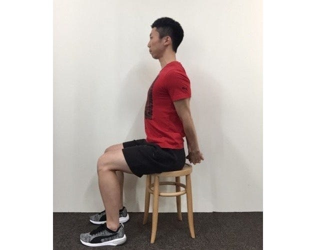 椅子に腰かけ後ろ手に組む