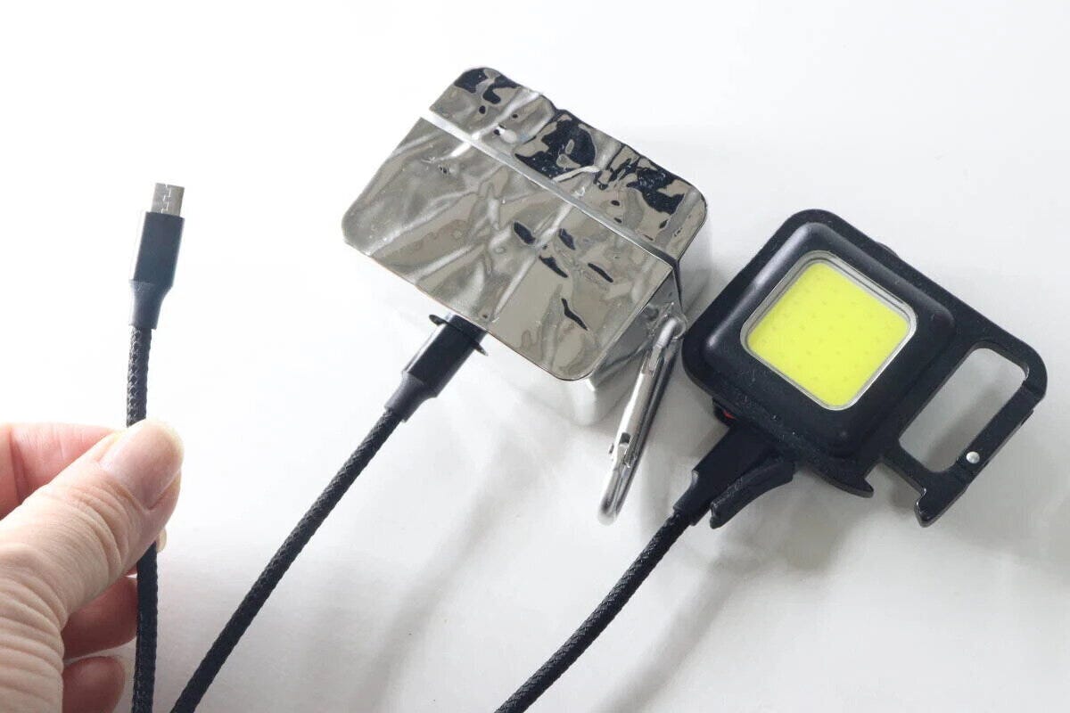 手で持った3in1ケーブルのmicroB端子と、充電中のワイヤレスイヤホンケースとライト