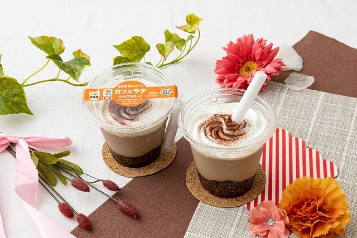 コースターに乗ったカフェラテわらびもち2個。ホイップとココアパウダーが特徴。