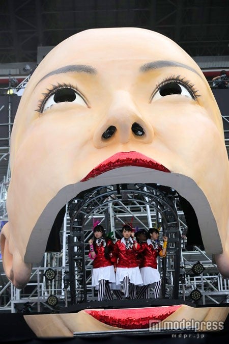 巨大なフェイスオブジェをバックにパフォーマンスしたももクロ。（Photo by 上飯坂一+Z）
