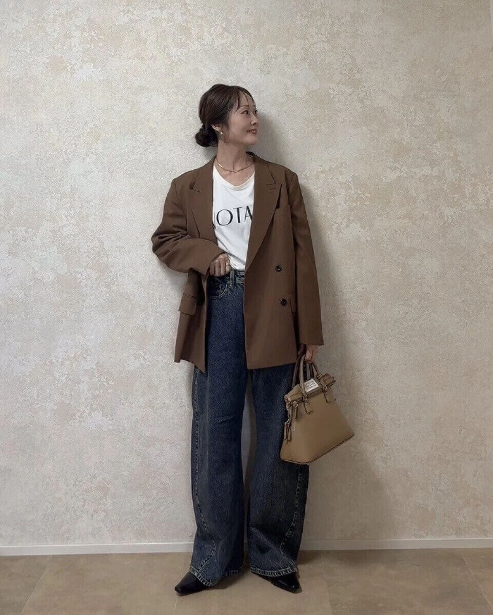 ブラウンのジャケットにロゴTとワイドデニムを合わせた女性のコーディネート