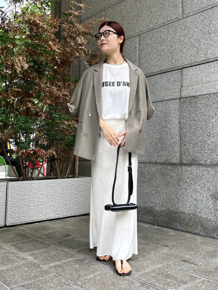 白いロゴTとベージュジャケット、白ナロースカートの女性 白いロゴTとベージュジャケット、白ナロースカートの女性