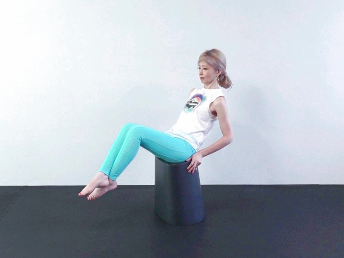 5:両手で椅子のふちをつかみ、上体を後ろに傾け、重ねた両脚を床から離します