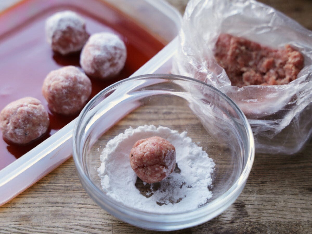 丸めた肉だねに片栗粉をまぶし耐熱容器のソースに入れる工程