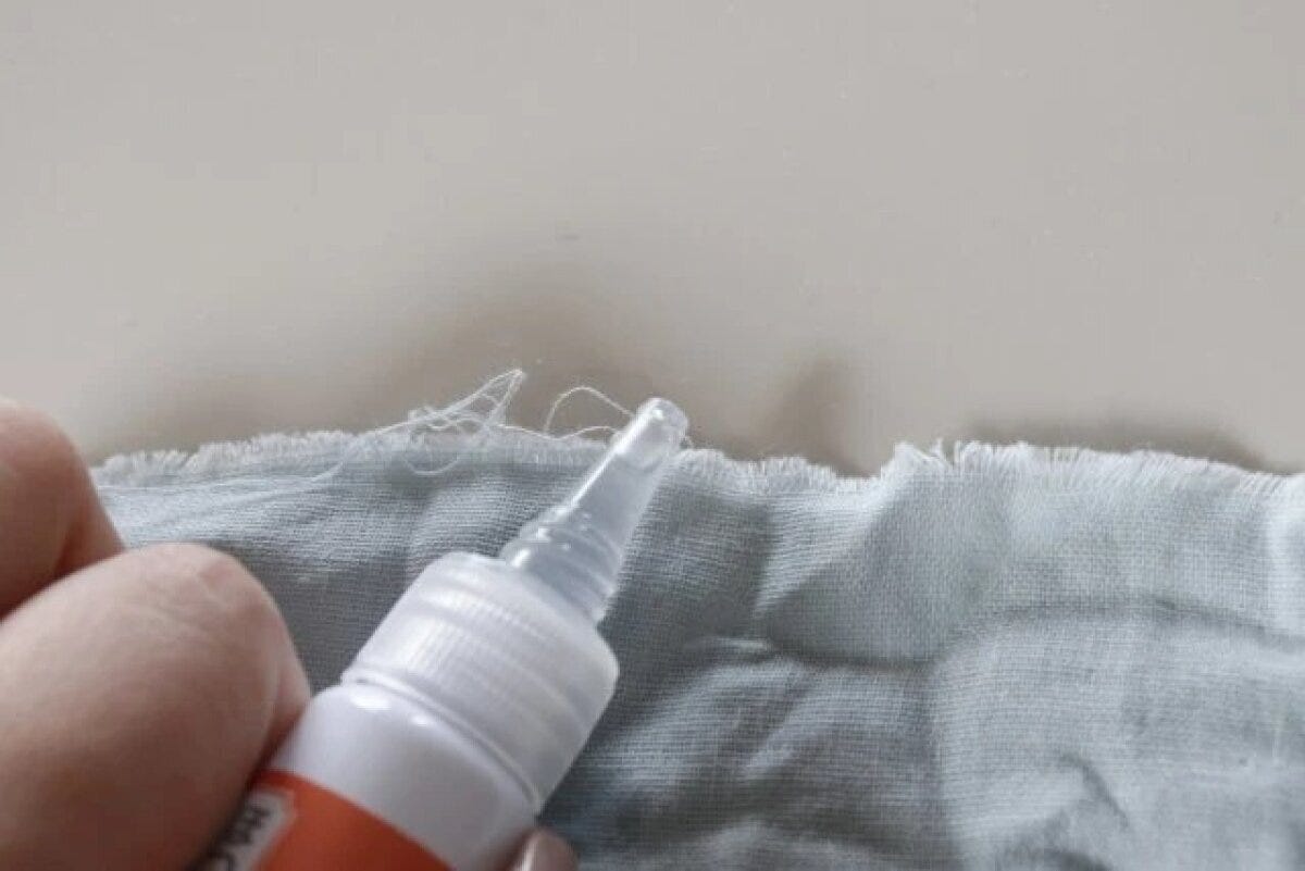 ほつれた布の端に「ほつれ止め液」を塗る手元
