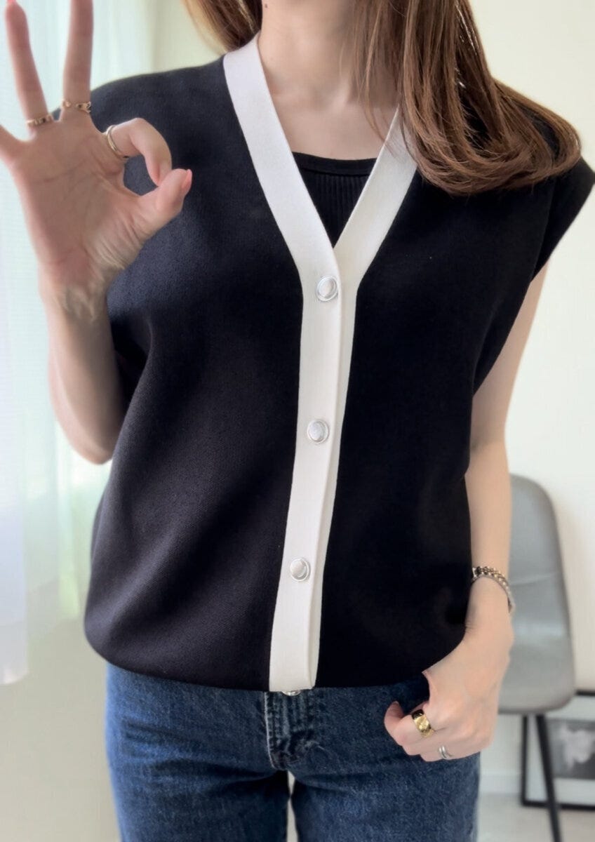 黒いブラキャミに白黒のVネックニットを重ね着した女性がOKサインをしている 黒いブラキャミに白黒のVネックニットを重ね着した女性がOKサインをしている