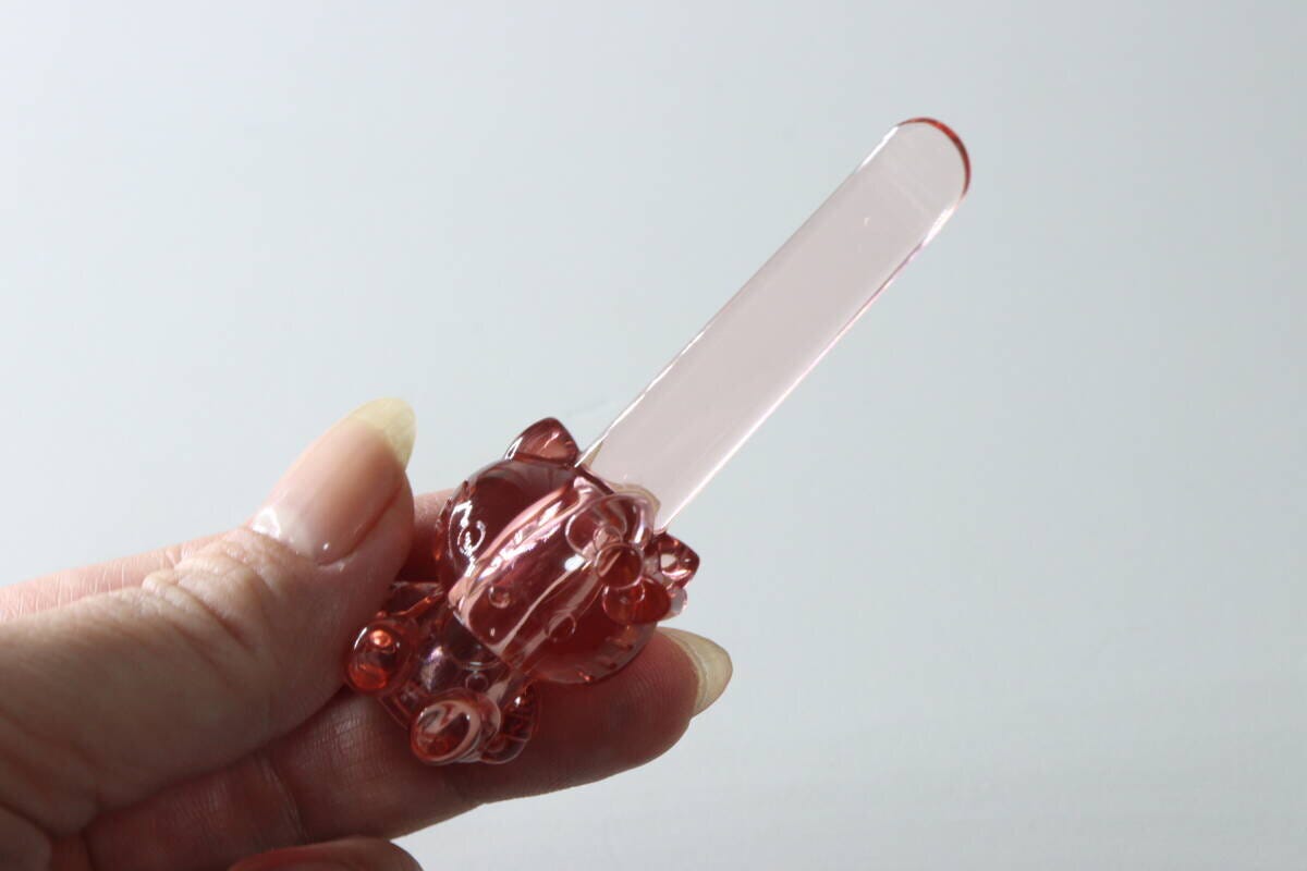 ピンク色のハローキティ立つスパチュラを指で持っている様子 ピンク色のハローキティ立つスパチュラを指で持っている様子