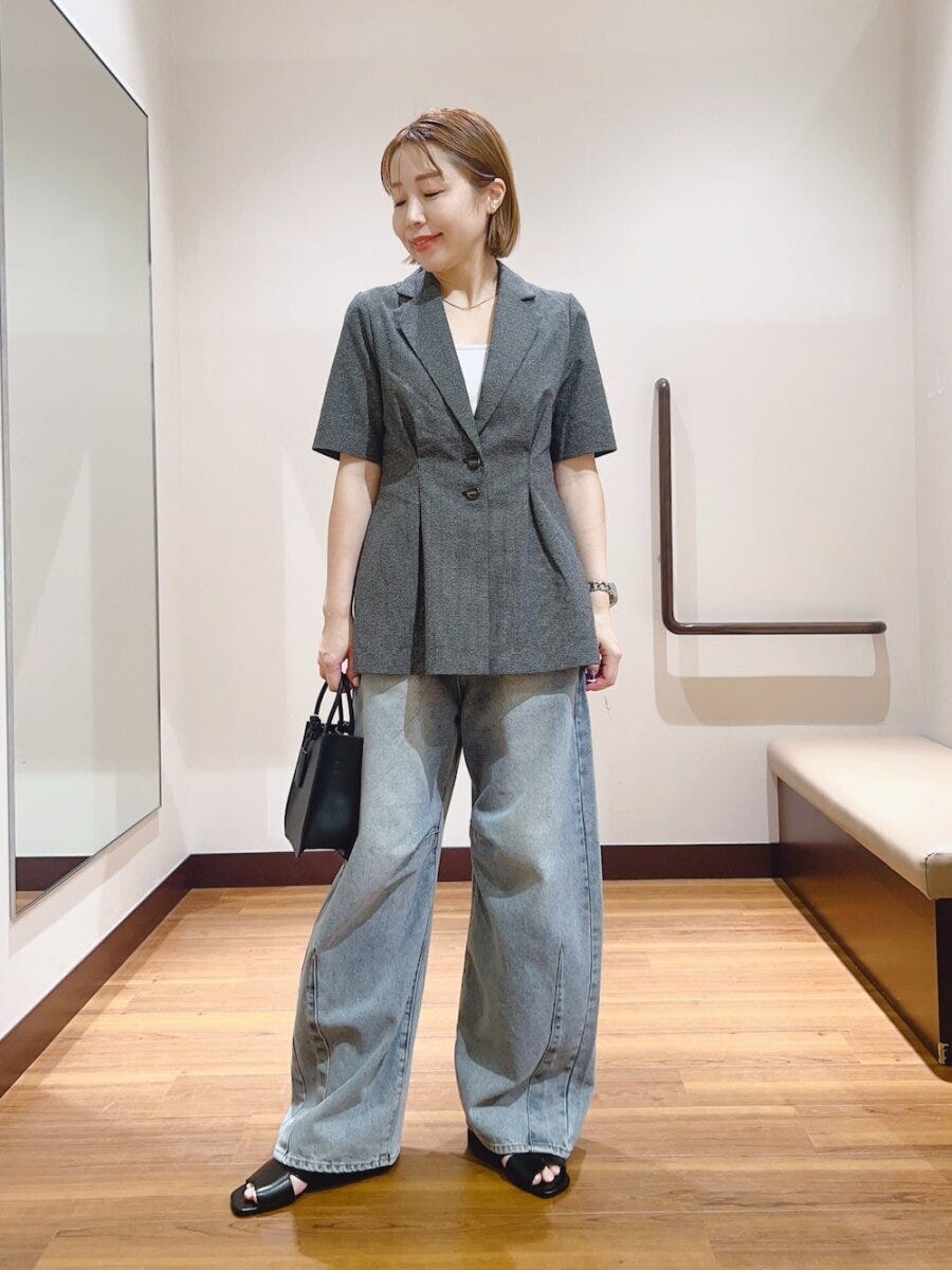 グレーの半袖ジャケットとライトブルーのワイドデニムを着用した女性
