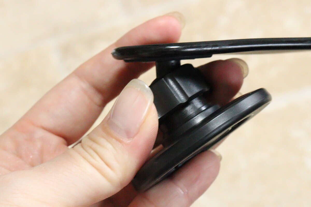 女性の手が車載スマホホルダーのヘッド部分を回して角度を調整している 女性の手が車載スマホホルダーのヘッド部分を回して角度を調整している