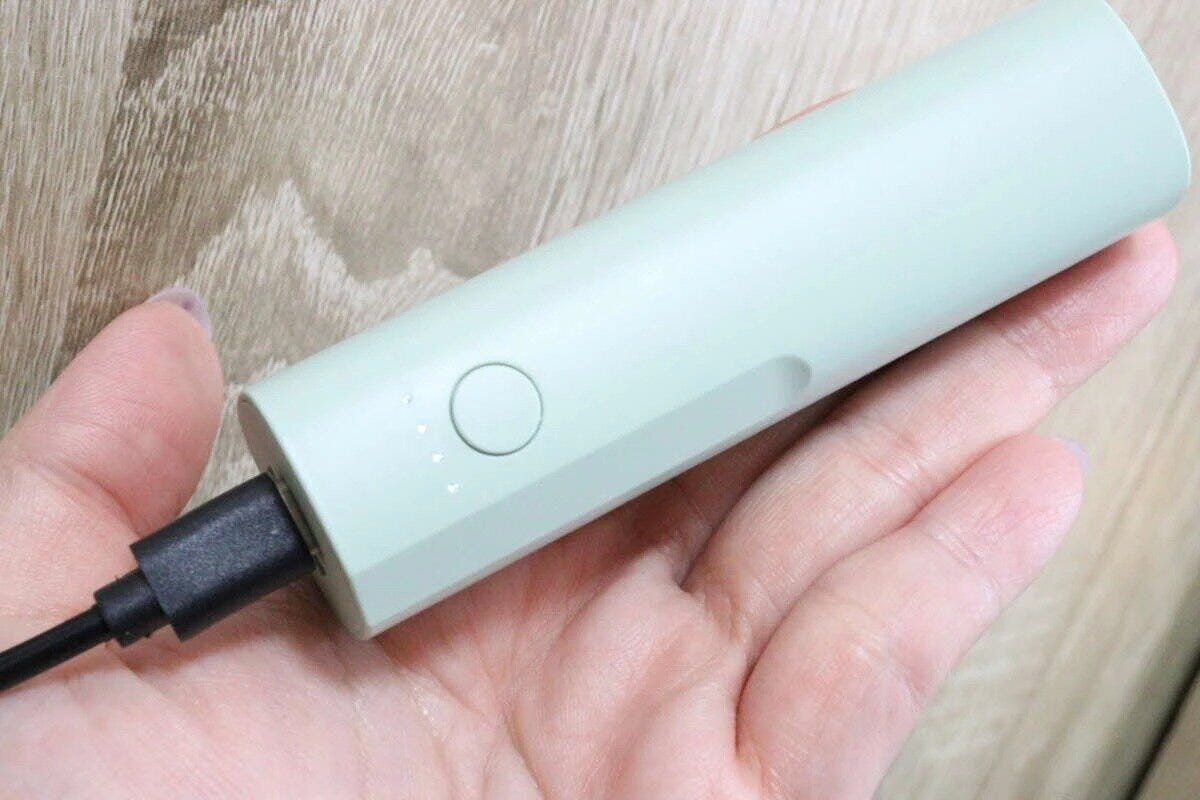 女性の手のひらに乗ったミントグリーンのモバイルバッテリー