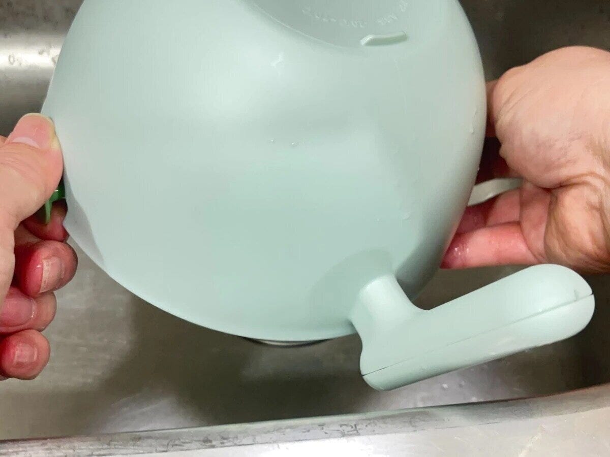 水切りザルボウルを傾け水切りする手元のアップ