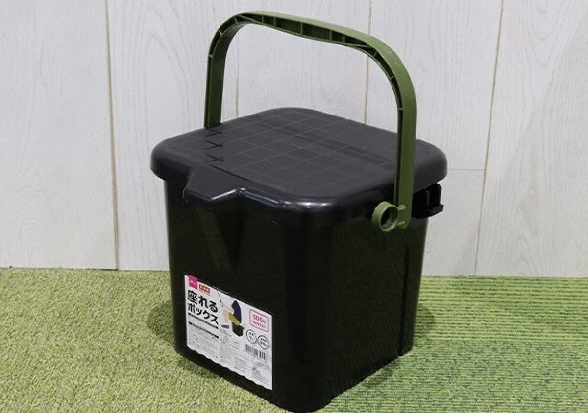黒い座れるボックスが緑の取っ手を上にして置かれている