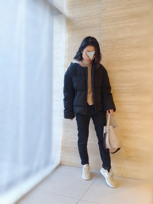 白のパーカーに黒のダウンを羽織り、スキニーパンツと白のスニーカー、ハンドバッグをコーディネート