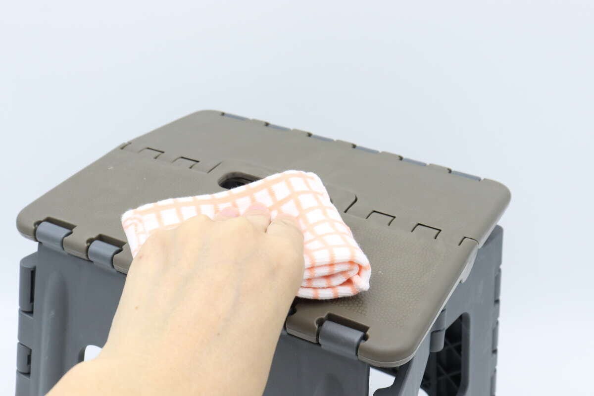 折りたたみイスの座面を布巾で拭いている手元 折りたたみイスの座面を布巾で拭いている手元