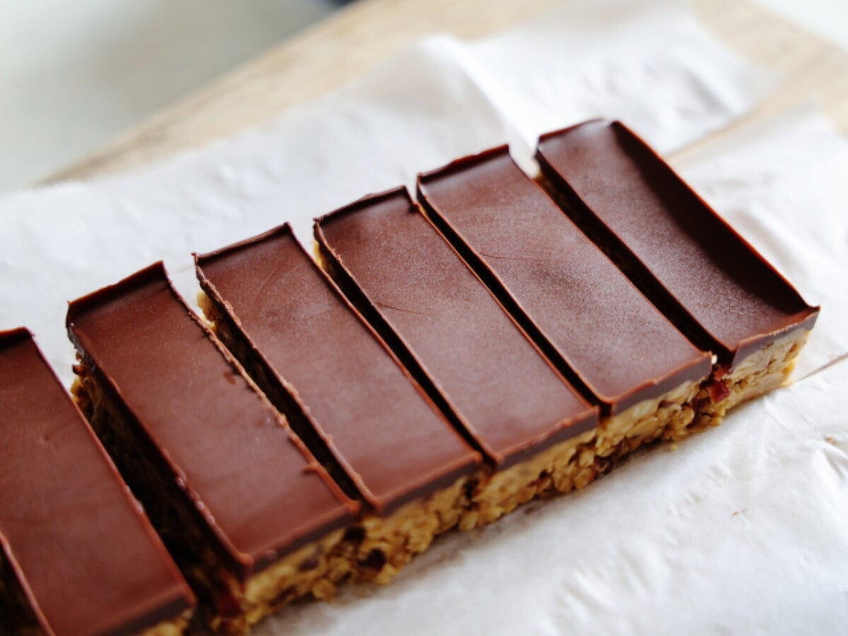 冷蔵庫で冷やし固められ、クッキングシートの上で均等な幅にカットされたチョコレートがけのクッキードゥバー。