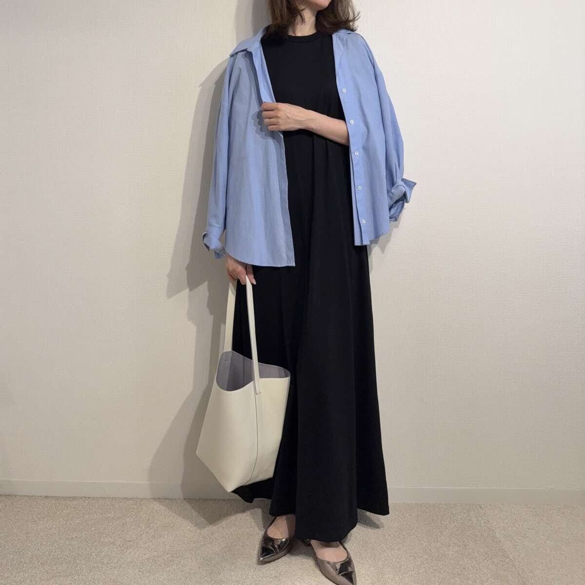 黒いワンピースに水色のシャツと白いバッグを合わせた女性の全身