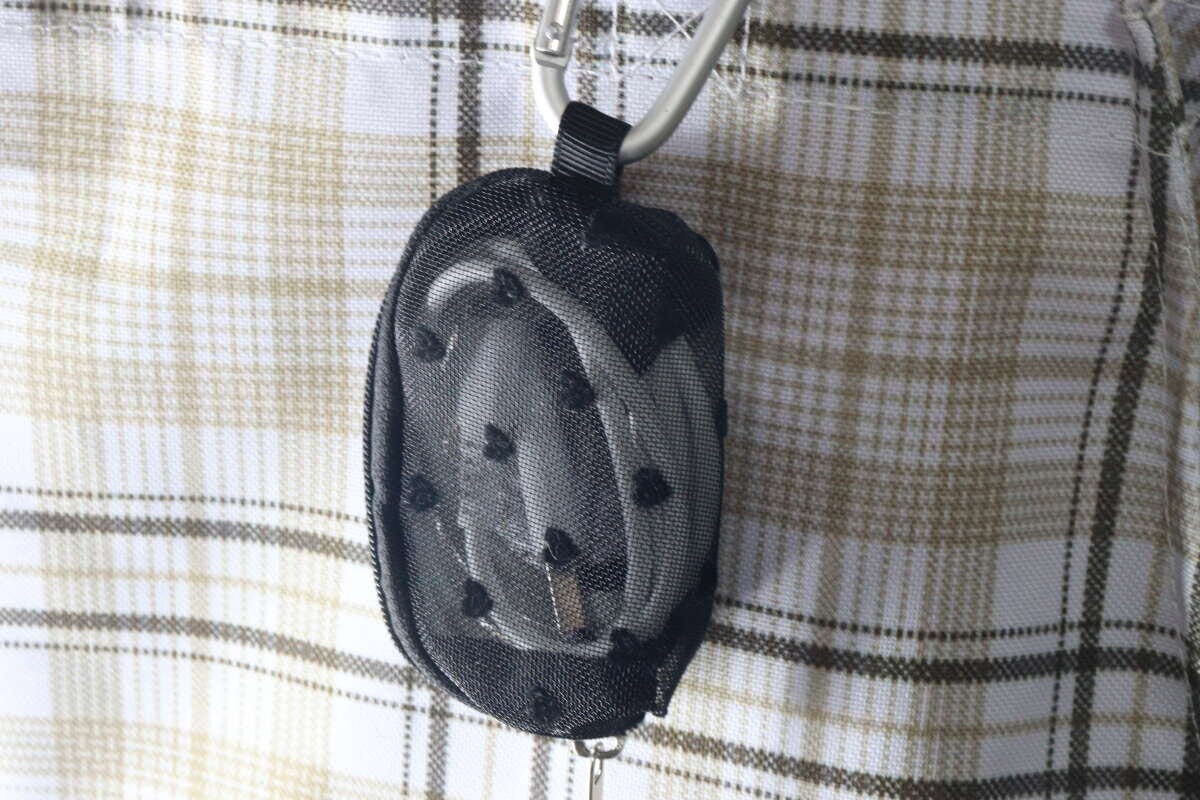 カラビナでバッグに吊り下げられた黒いメッシュポーチ カラビナでバッグに吊り下げられた黒いメッシュポーチ