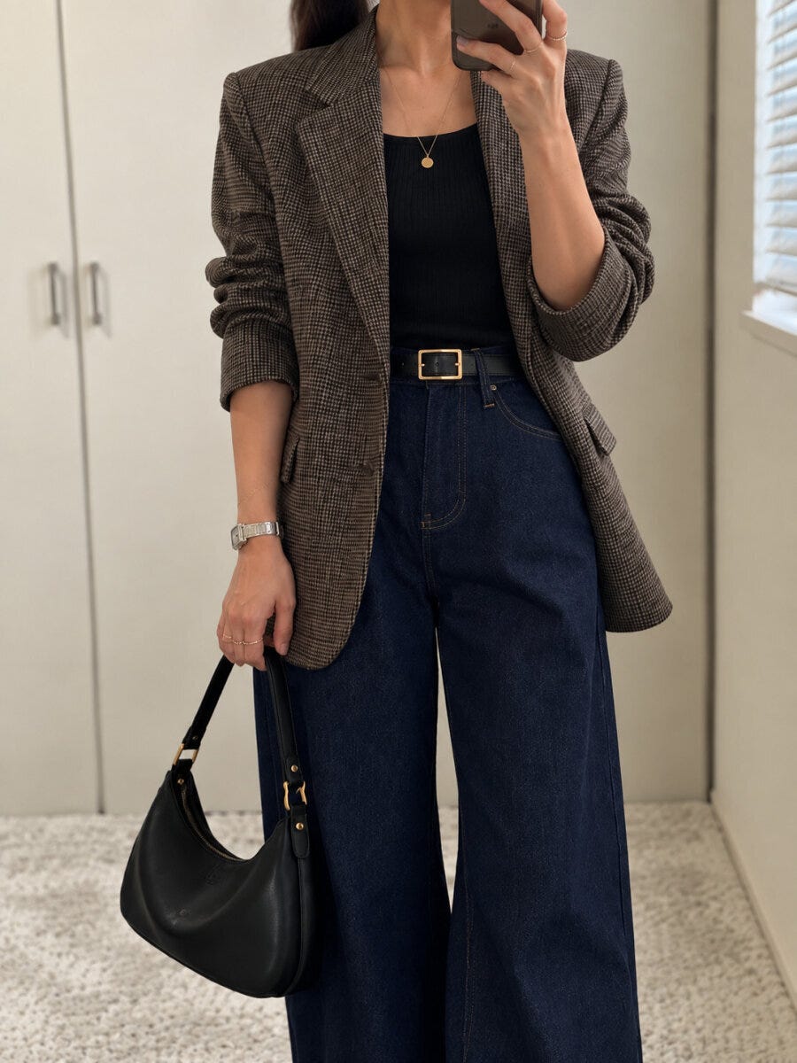 チェック柄ジャケットと濃紺ジーンズの秋コーデでスマホを持つ女性
