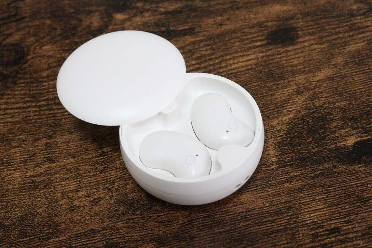 木目調のテーブルに置かれた、白い丸い充電ケースと寝ホン 木目調のテーブルに置かれた、白い丸い充電ケースと寝ホン