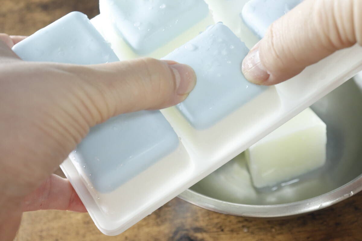 凍った牛乳キューブを指で押して製氷皿から取り出している手元