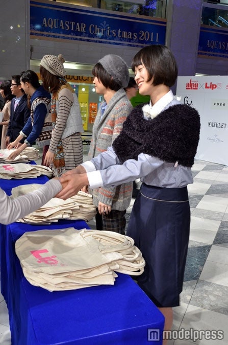 来場者へ笑顔でプレゼントを手渡すモデルたち