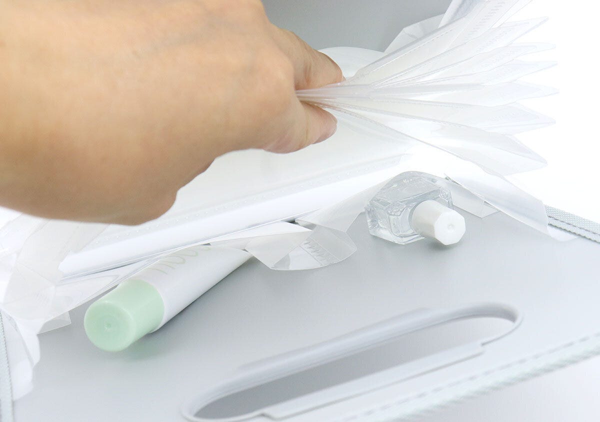 グレーのコクヨお薬ファイルの内ポケットに軟膏と消毒液を収納している手元