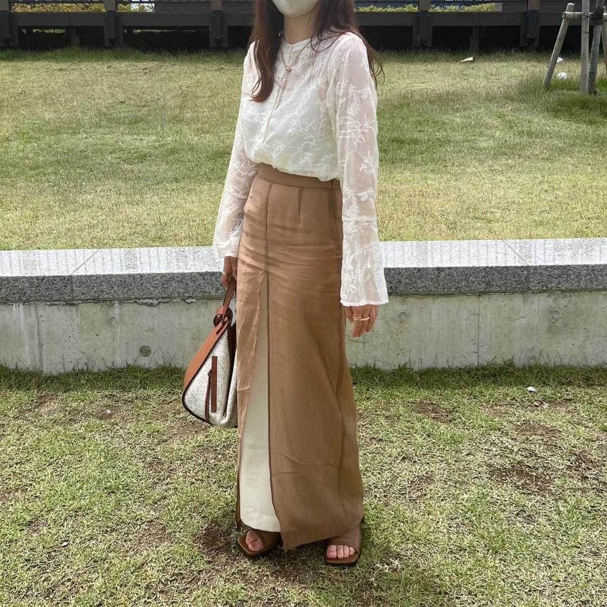 ホワイト系の透け感ブラウスを着ている女性の写真