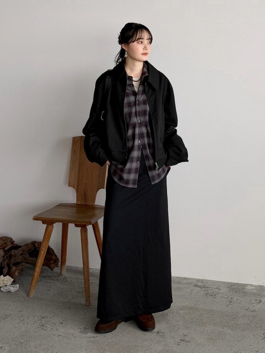黒のブルゾンとロングスカートのシックな装いにチェックシャツをインしたスタイル