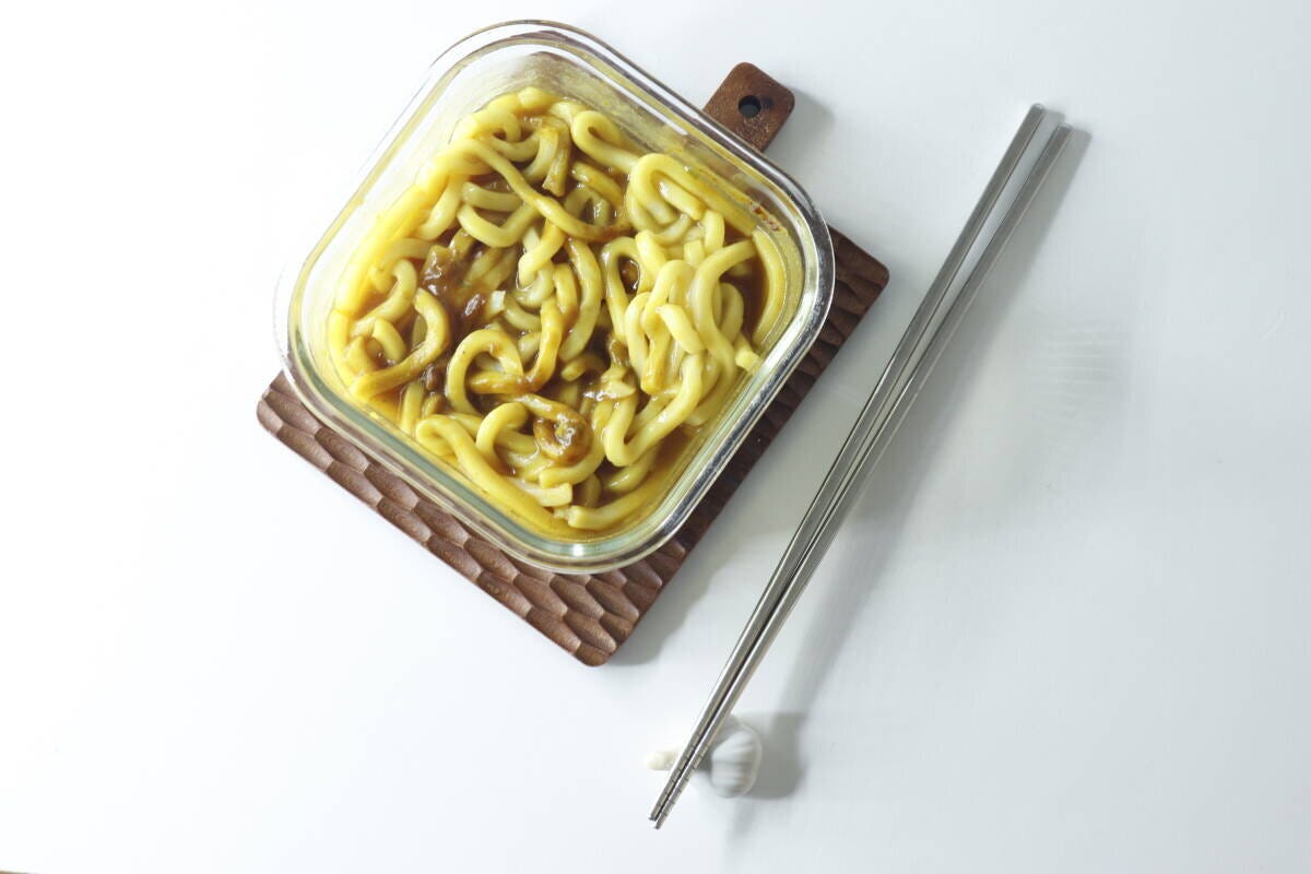 透明な耐熱容器に入ったカレーうどんと、横に置かれた箸 透明な耐熱容器に入ったカレーうどんと、横に置かれた箸