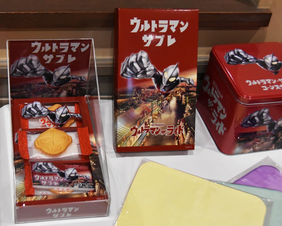 ウルトラマンサブレ（ウルトラマン・ザ・ライド版） 12枚入り100園（左）、ウルトラマン・ザ・ライドコーンスナック（チーズ味）150園（右）