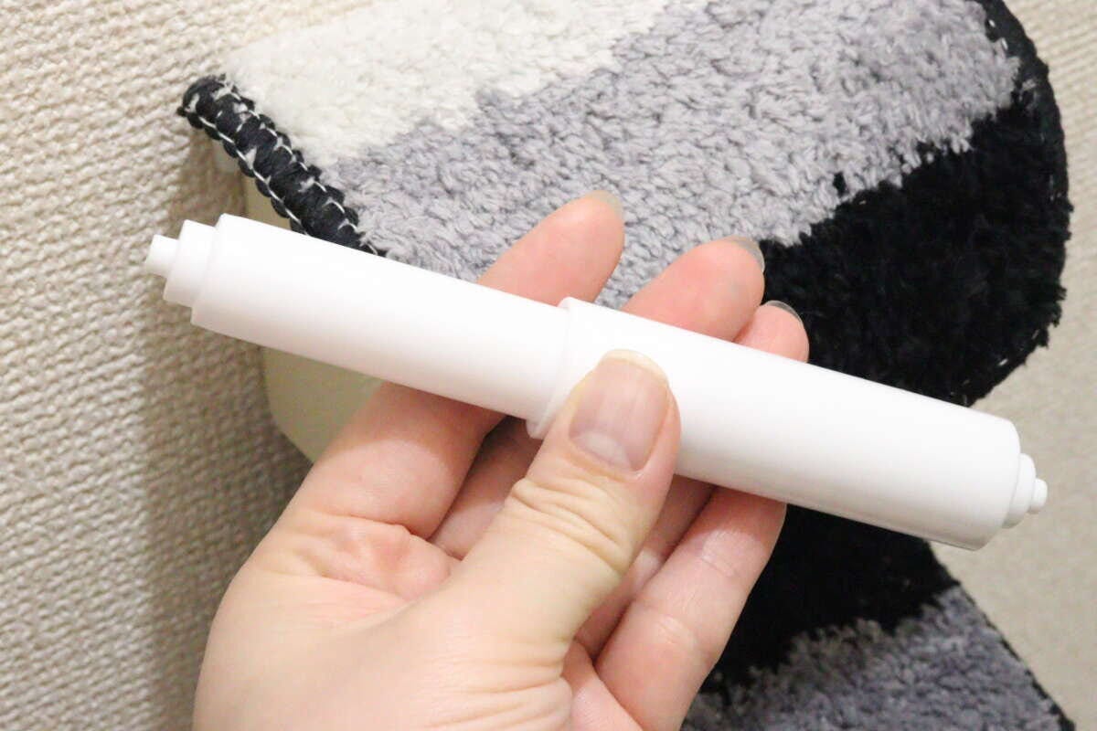女性の手が新しい白いトイレットペーパー替え芯ホルダーを手に持っている 女性の手が新しい白いトイレットペーパー替え芯ホルダーを手に持っている