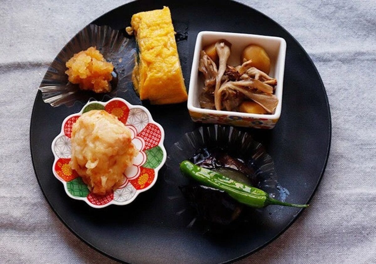 黒い丸皿（深月レンジ食器）に和食のおかずが盛り付けられている