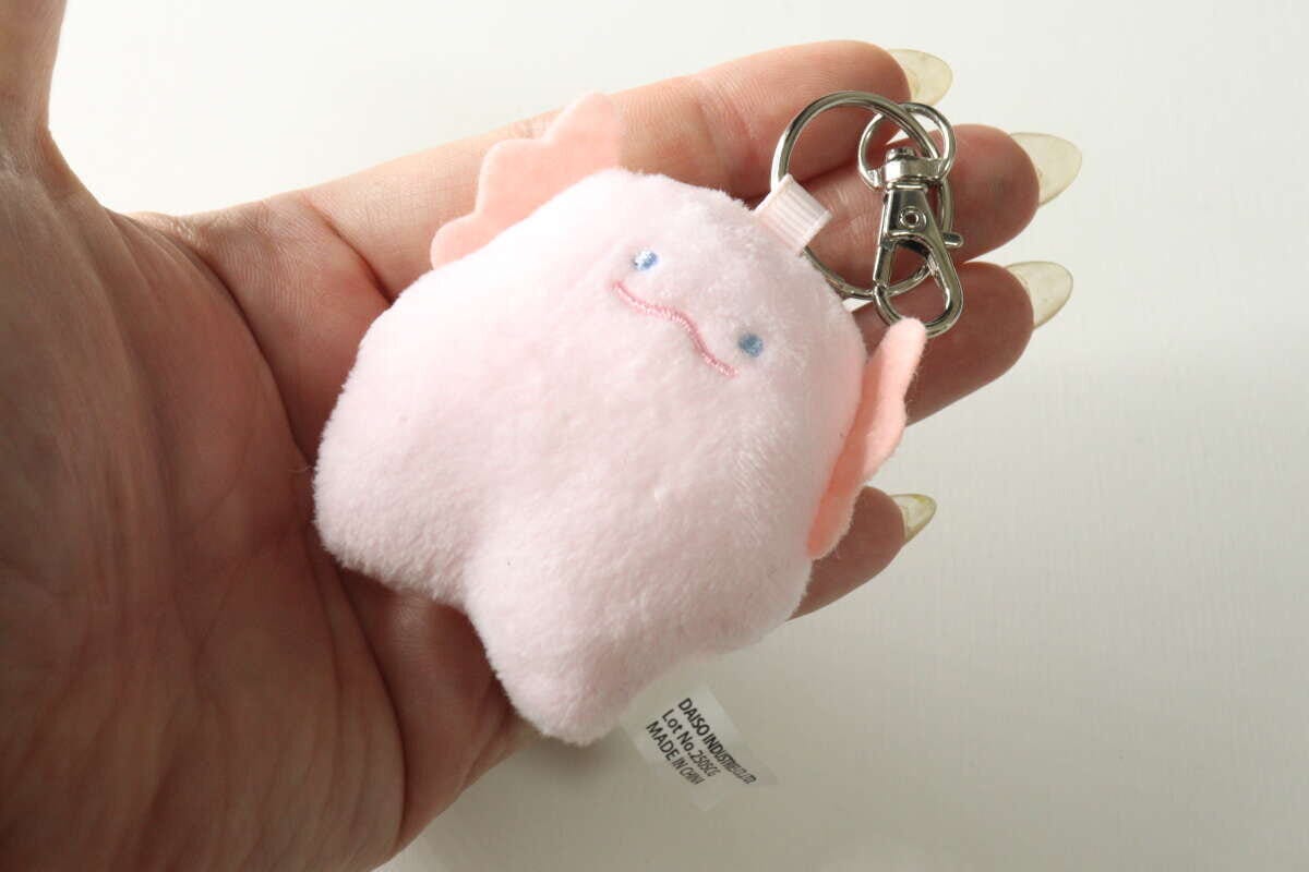 女性の手のひらに乗せられた手のひらサイズのピンク色のマスコット 女性の手のひらに乗せられた手のひらサイズのピンク色のマスコット
