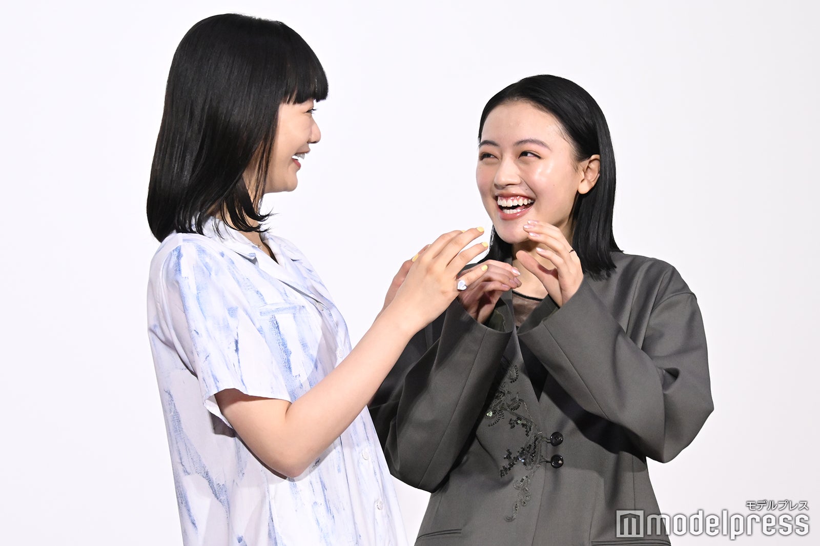 記者にハートポーズを求められ照れ笑いを浮かべる見上愛、上坂樹里（C）モデルプレス