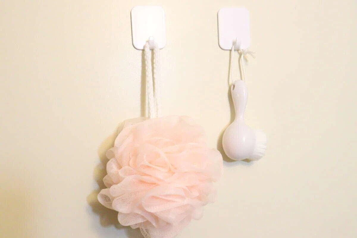 浴室の壁にフックを貼り付けて収納する様子