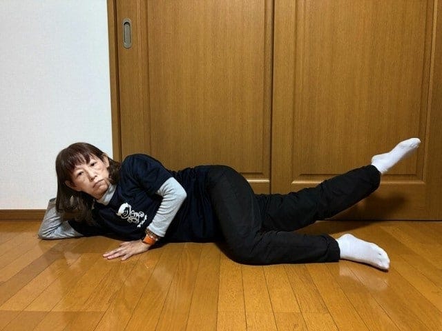 横になった状態で上の足を前にクロスさせ、下にある足を床から浮かせよう