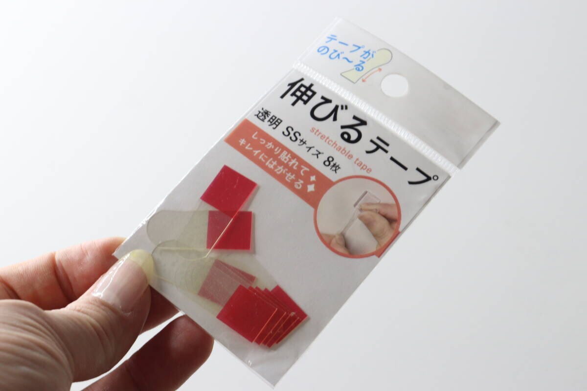 女性の手がダイソー「伸びるテープ」のパッケージを斜めに持っている様子