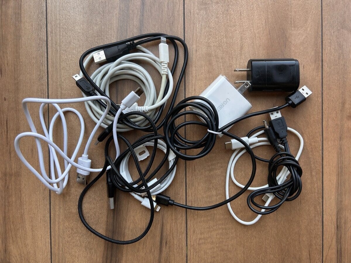 木のテーブルにまとめられた絡まったコード類と充電アダプター