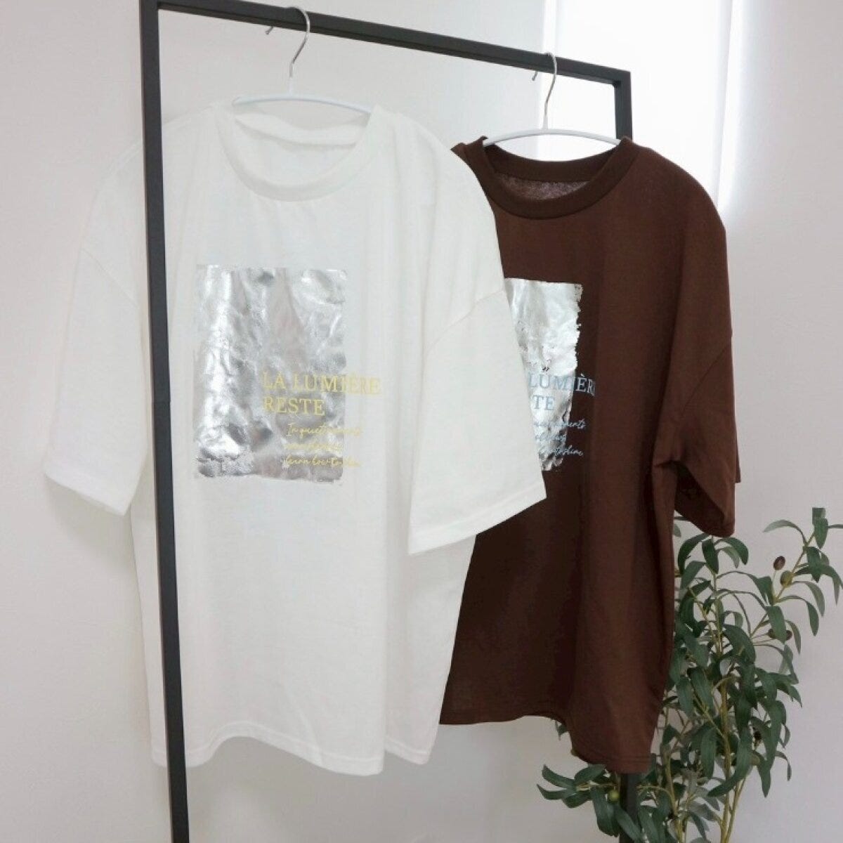 白と茶色のプリントTシャツがハンガーラックにかけられている