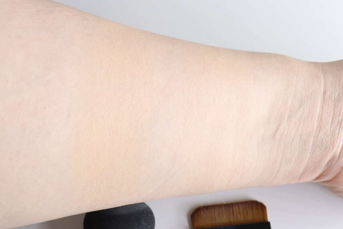 ファンデーションを塗布した腕とブラシ、スポンジ